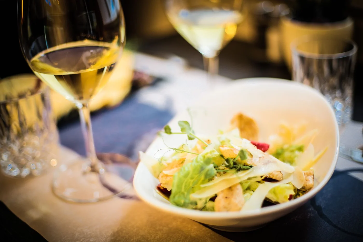 Seasonal salad and glasses of white wine on a dinner party table served at home by a private chef