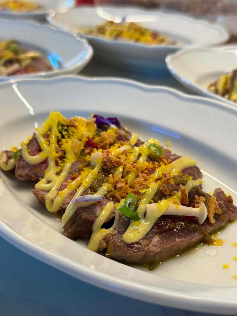 Sliced beef with a yellow sauce, a Chef Max Delmont creation
