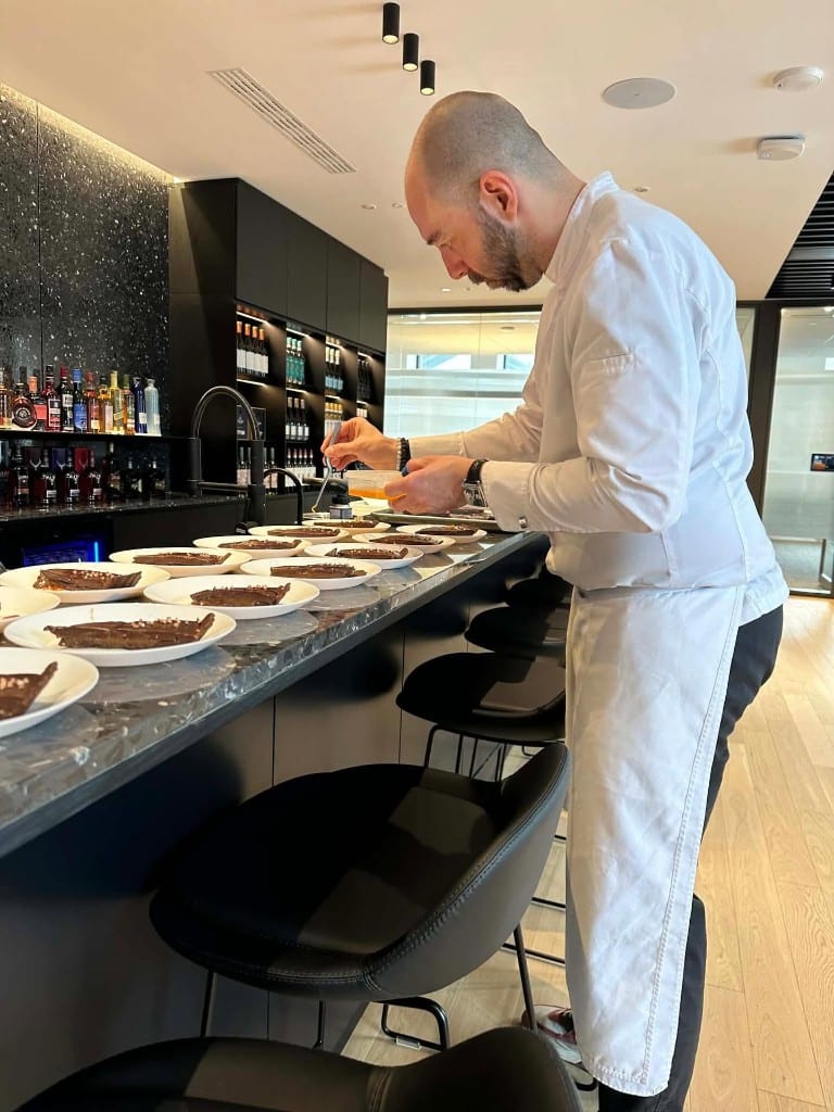 Chef Max Delmont plating desserts at the bar