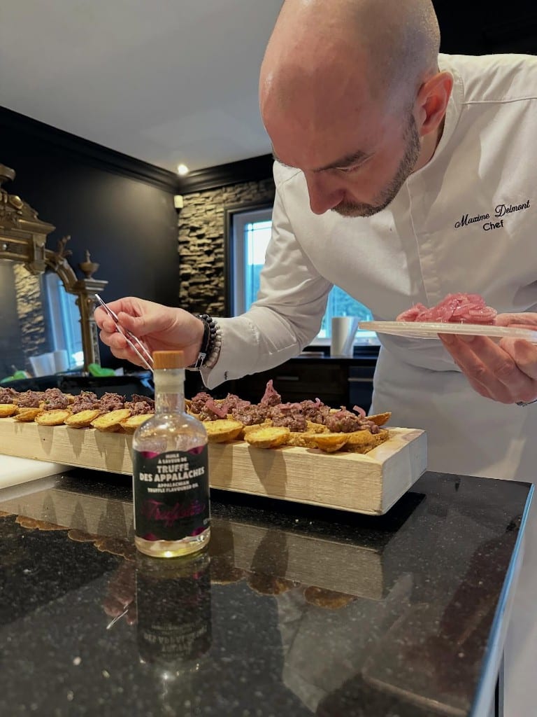 Chef Max Delmont drizzling truffle oil over canapés