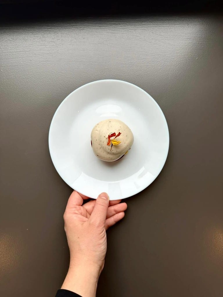 Sphere dessert placed by hand onto a plate