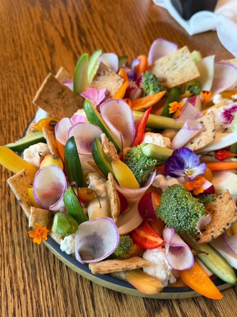 Crudités platter with edible flowers and crackers plated by Chef Max Delmont