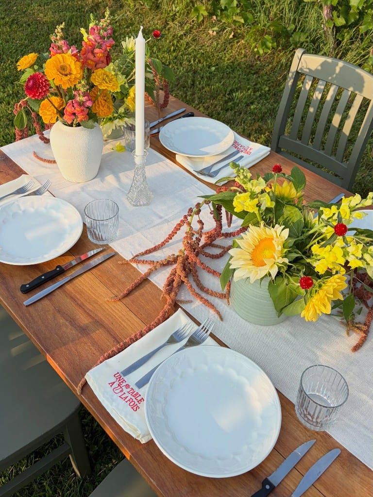 Set table with flowers and napkins reading “une table à la fois”